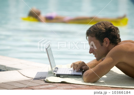 A man poolside using a laptop computer 10366184