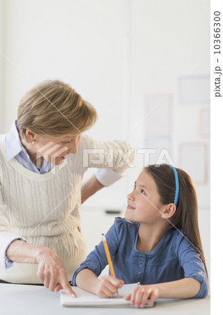 Teacher helping schoolgirl (8-9) at school 10366300
