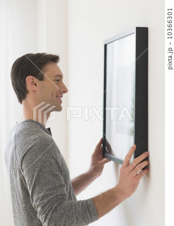 Man hanging picture on wall 10366301