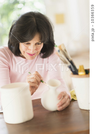Senior woman painting handmade pottery 10366359