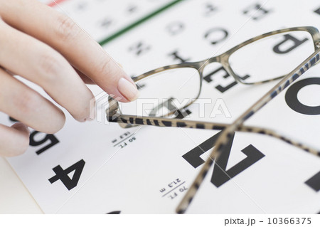 Close up of woman's hands holding glasses above eye chart, studio shot 10366375