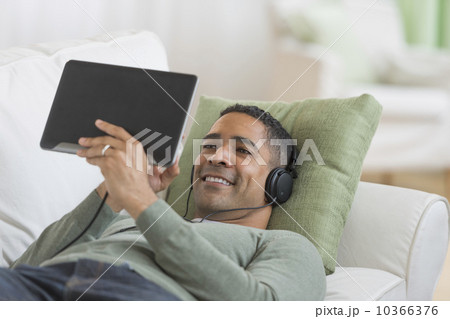 Man listening music from digital tablet on sofa 10366376