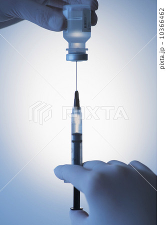 Close up of hands in surgical gloves preparing syringe for injection, studio shot 10366462