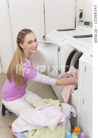 Woman loading laundry into washing machine 10366547