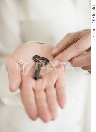 Female hand holding heart-shaped key 10366669