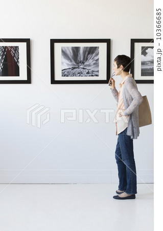 Woman watching photographs in art gallery 10366685