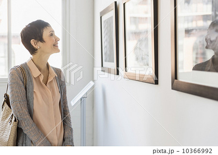 Woman watching photographs in art gallery 10366992