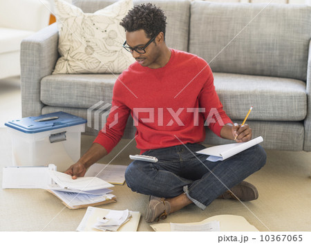 Man sitting on floor in living room and calculating bills Man sitting on floor in living room and calculating bills 10367065