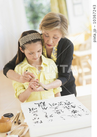 Grandmother and granddaughter (8-9) painting japanese symbols 10367243