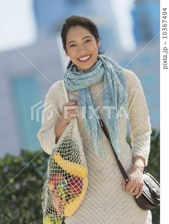 Portrait of smiling young woman with grocery shopping bag 10367494