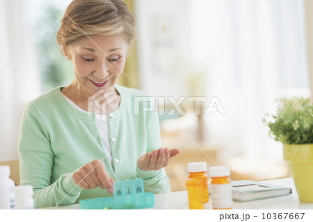 Senior woman organizing medicine in box 10367667
