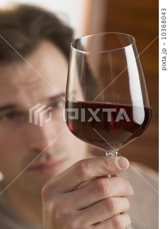 Man examining upheld glass of wine 10368043