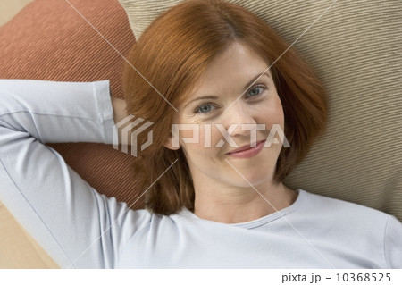 Smiling redheaded woman lying on pillows Smiling redheaded woman lying on pillows 10368525