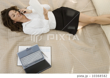 Businesswoman on mobile phone while lying on bed 10368582