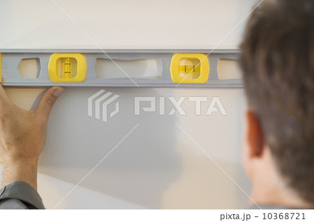 Man holding a level against a wall 10368721