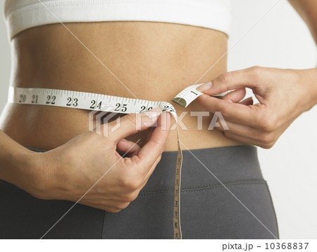 Closeup of woman measuring her waist Closeup of woman measuring her waist 10368837