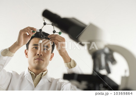 Scientist with microscope holding molecular model 10369864