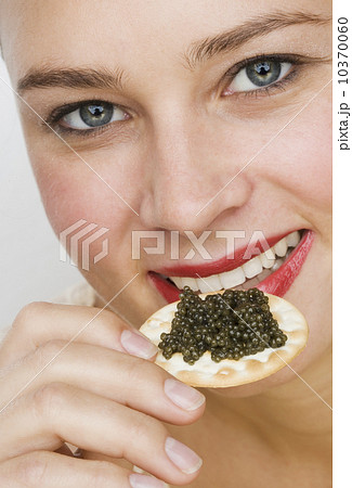 Close up of woman eating caviar on a cracker Close up of woman eating caviar on a cracker 10370060