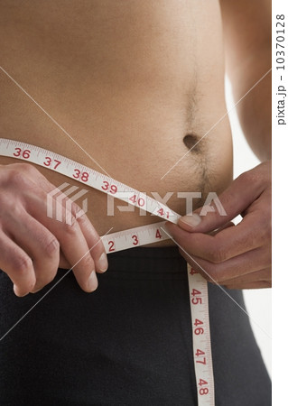 Man measuring his waist Man measuring his waist 10370128
