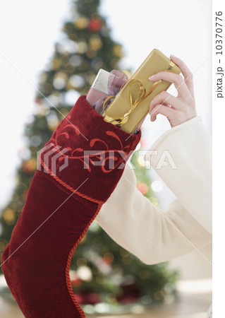 Woman stuffing gifts into Christmas stocking 10370776