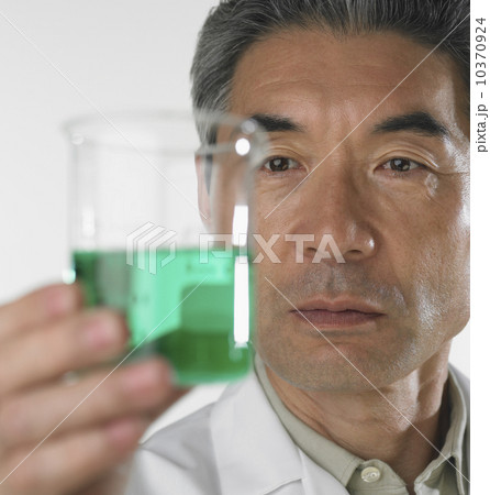 Man looking at beaker of fluid 10370924