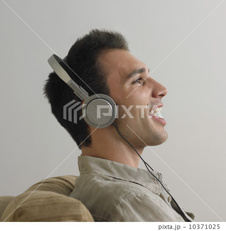 Man sitting and listening to music on headphones 10371025