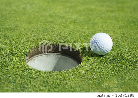 Golf ball near cup on putting green outdoors Golf ball near cup on putting green outdoors 10371299