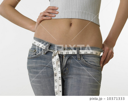Woman with bare midriff using tape measure as belt Woman with bare midriff using tape measure as belt 10371333