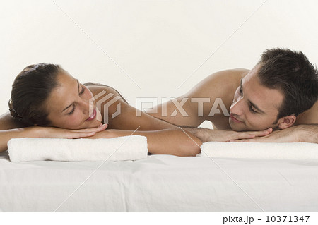 Couple laying next to each other and leaning on towels 10371347