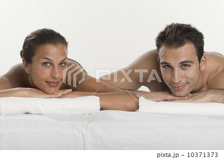 Couple laying next to each other and leaning on towels 10371373