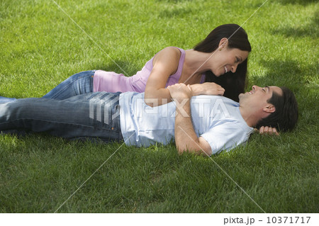 Couple laying in grass and smiling at each other 10371717