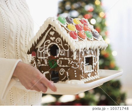 Woman holding gingerbread house on tray 10371748