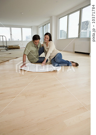 Couple looking at blueprints on floor in new house Couple looking at blueprints on floor in new house 10371784