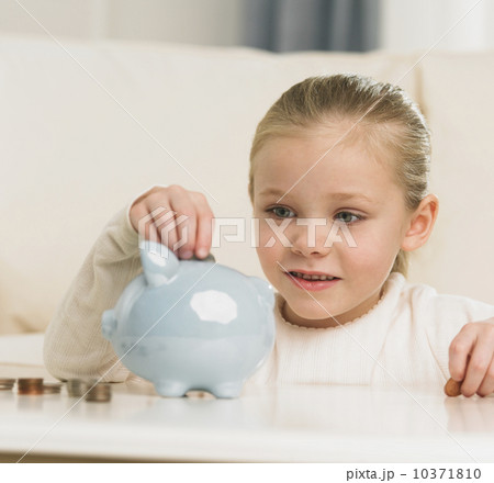 Young girl putting change in piggy bank Young girl putting change in piggy bank 10371810