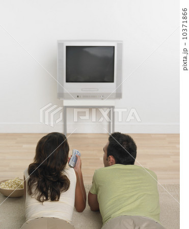 Couple laying on floor with popcorn watching television Couple laying on floor with popcorn watching television 10371866