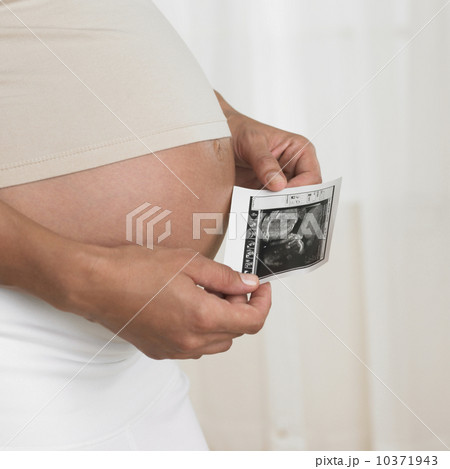 Pregnant woman holding ultrasound next to stomach Pregnant woman holding ultrasound next to stomach 10371943