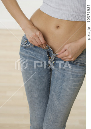 Close up of woman buttoning jeans 10371985