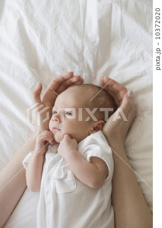 Mother holding hands around newborn baby's head 10372020