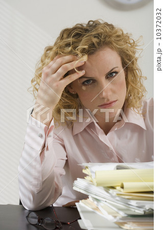 Businesswoman rubbing temple and looking at paperwork Businesswoman rubbing temple and looking at paperwork 10372032
