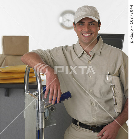 Deliveryman smiling and leaning on hand truck 10372044