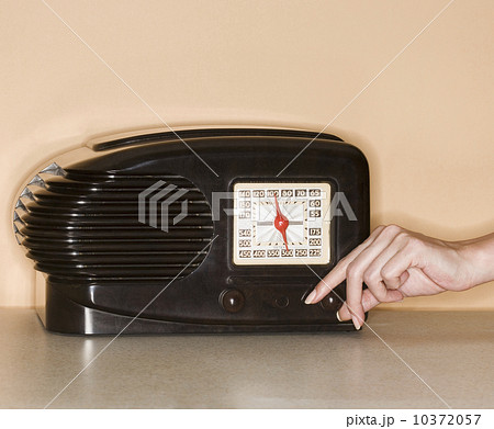 Woman turning knob on old fashioned radio 10372057