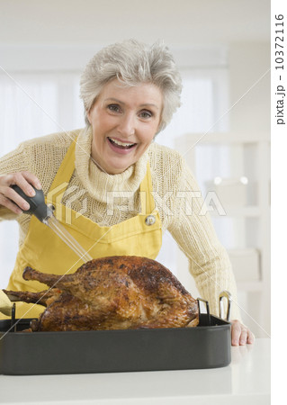 Senior woman basting roast turkey 10372116