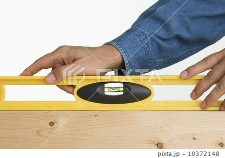 Close up of man using level on piece of wood 10372148