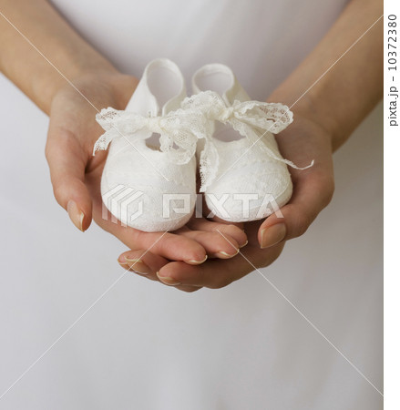 Close up of woman holding baby shoes 10372380