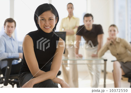 Portrait of businesswoman with coworkers in background Portrait of businesswoman with coworkers in background 10372550