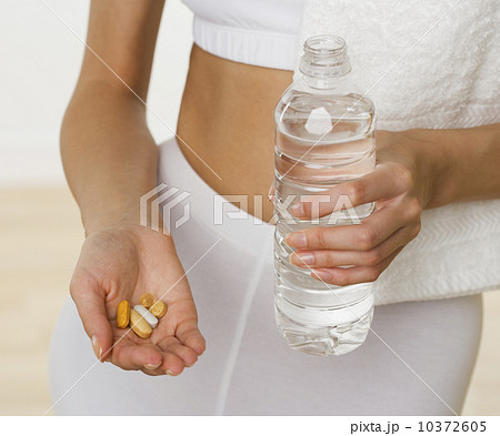 Close up of woman holding vitamins and bottle of water 10372605