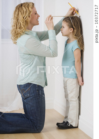 Mother marking daughter’s height on wall 10372717