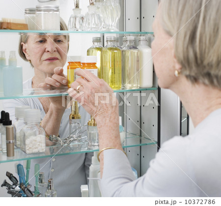 Senior woman looking in medicine cabinet 10372786