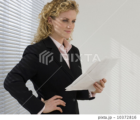 Businesswoman reading paperwork next to window 10372816