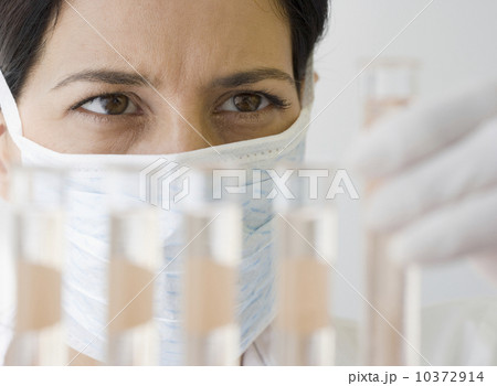 Female scientist looking at vials of liquid 10372914
